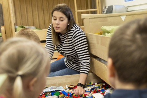 lapset ja opettaja leikkivät legoilla päiväkodissa