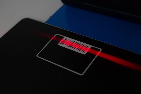 Lainausautomaatin viivakoodilukijan punainen säde mustalla pohjalla.