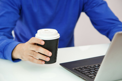 Hands holding coffee and laptop