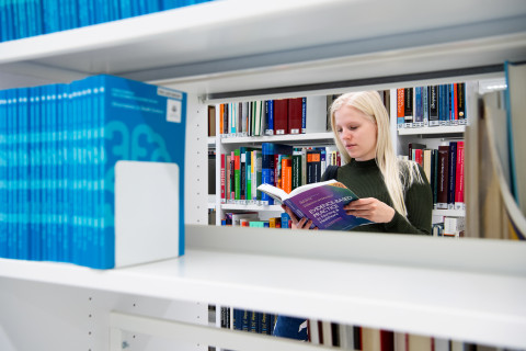 Opiskelija lukee kirjaa UEFin kirjastossa.