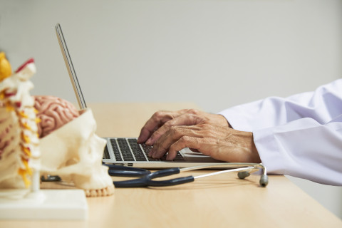 Lääkäri kannettavan tietokoneen ääressä