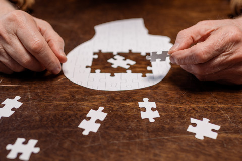 Kädet kokoamassa palapeliä.