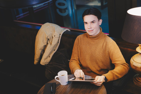 Nuori mies istuu kahvilassa
