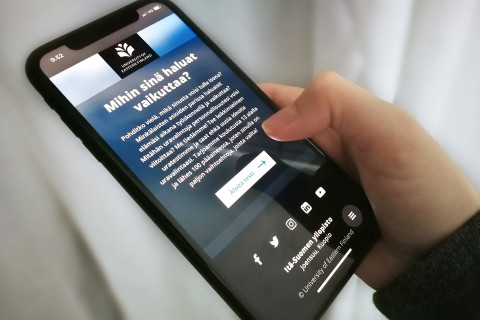 Puhelin, jossa uravalintatesti avoinan, kädessä