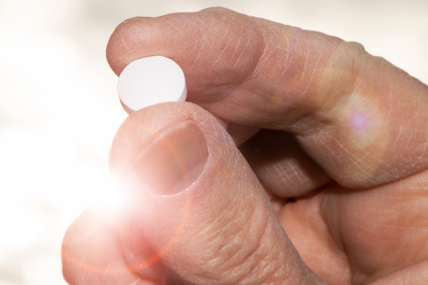 Hand holding a vitamin D pill.