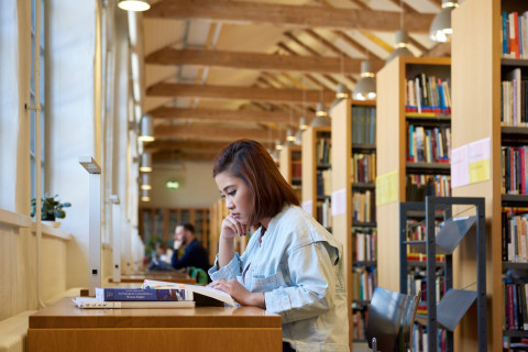 A woman is reading a book in a library