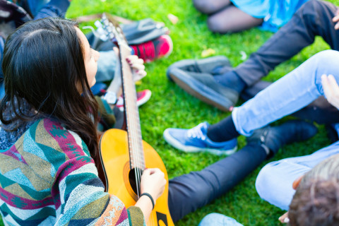 Young people playing guitar and singing.