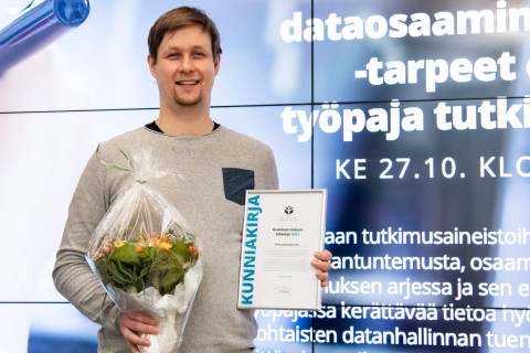 Mies, kukkakimppu, kunniakirja, avoin tiede, vaikuttavuuden talo.