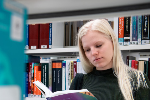 UEF-lähettiläs Mirka Nieminen kirjastossa selaamassa kirjaa