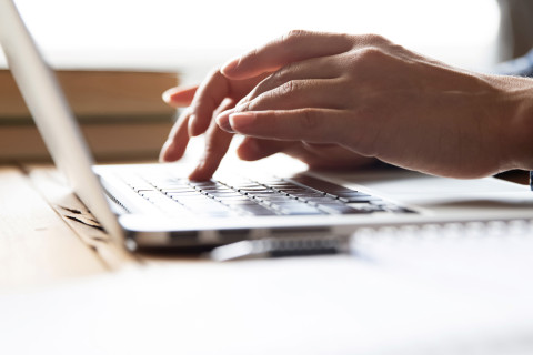 Kannettava tietokone ja kädet.