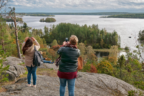 Kaksi naista ottaa korkealta mäeltä kuvia järvestä.