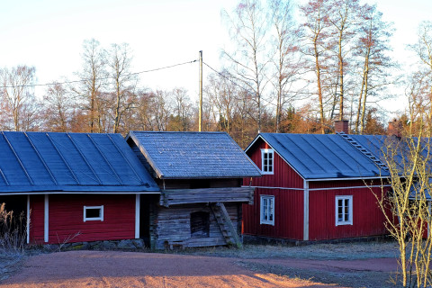 Punaisia rakennuksia ja harmaa aitta maatalon pihapiirissä.