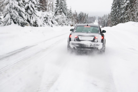 Auto ajaa lumisella tiellä.