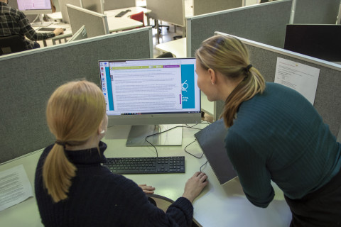 Two library customers looking at an article on a computer screen