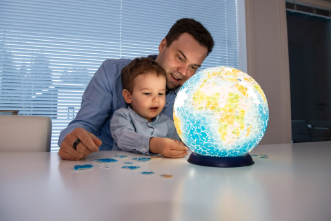 Adult and child playing with a jigsaw puzzle globe.