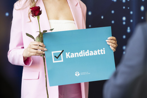 Opiskelija pitää onnittelukylttiä publiikissa.