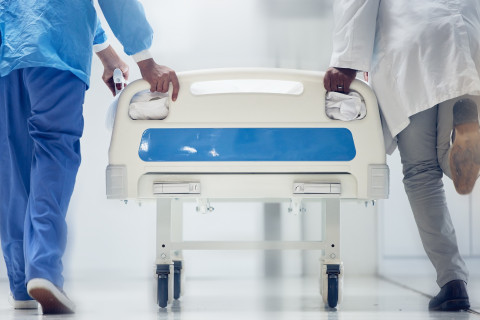 Kaksi sairaanhoitajaa kuljettaa sairaalasänkyä.