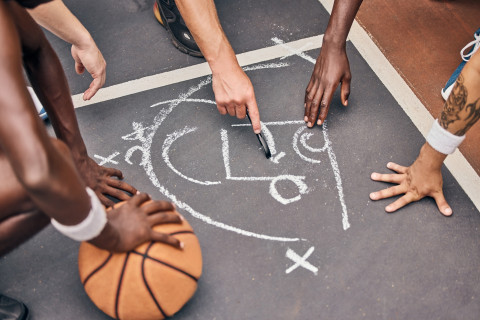 Asfalttiin piirretty koripallopelin taktiikkasuunnitelma.