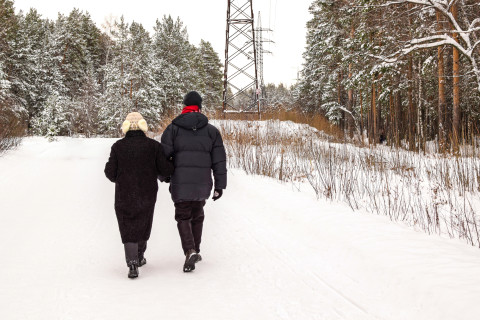 Kaksi ihmistä kävelee käsikynkässä talvisella tiellä.