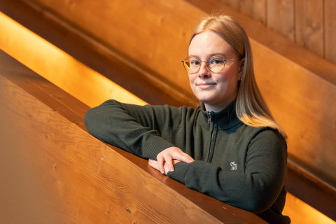 Metsätieteen opiskelija Helmi Karppinen nojaamassa puiseen porraskaiteeseen