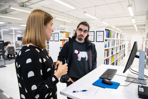Kirjaston tietopalveluneuvoja ja asiakas kirjastossa.