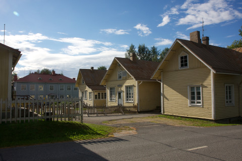 Three old wooden houses in front a larger wooden building