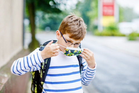 Koululainen laittaa suojamaskia kasvoille.