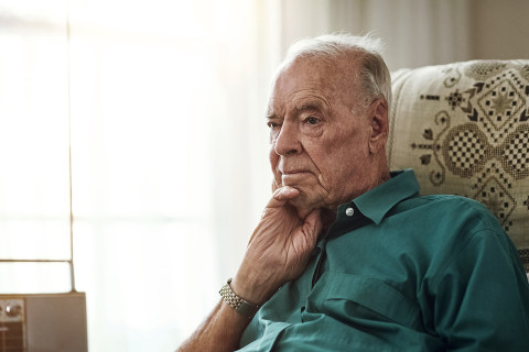 Vanhus mies kuuntelee radiota sohvalla.