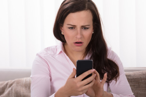 Shocked woman looking at mobile phone.