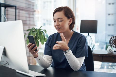 Sairaanhoitaja keskustelee mobiilipuhelin kädessään.