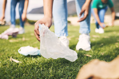 Ihmisiä keräämässä roskia nurmikolta.