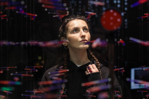 Henkilö punertavien valoheijastusten keskellä pimeässä