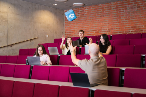 Luentosali, jossa opiskelijoita. Heittomikki ilmassa.