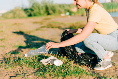 Nainen kerää muovijätettä ulkona.
