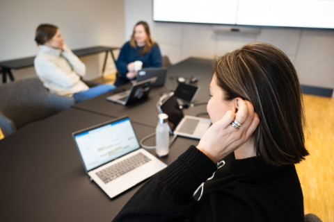 Kokouksen osallistuja koskettaa kuulolaitetta.