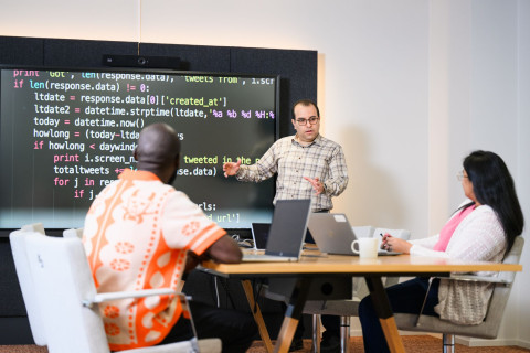 Man teaching two students in front of a screen