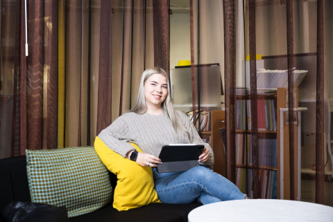 Opiskelija kampuskirjastossa sohvalla iPad kädessään