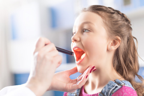 Lääkäri tutkii lapsen kurkkua.