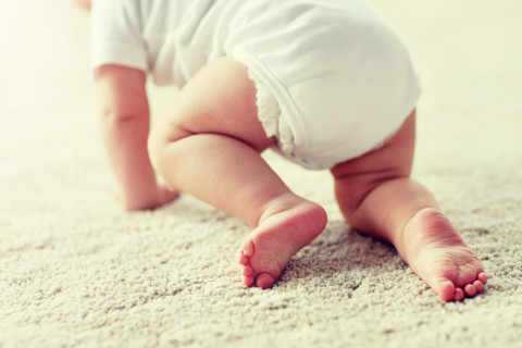 Vauva konttaa matolla.