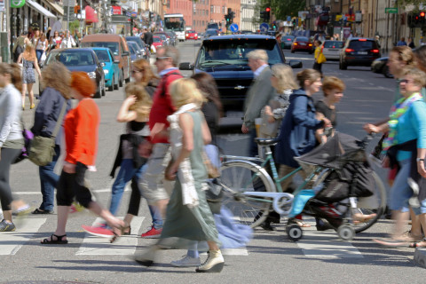 Ihmisiä kävelemässä suojatiellä vilkasliikenteisellä kadulla.