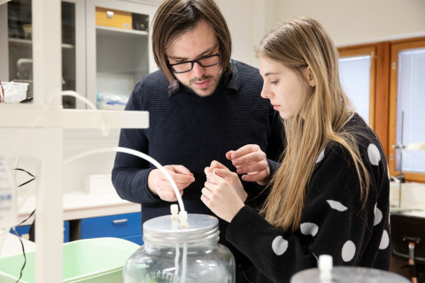 Two people in a laboratory-like environment examining something together.