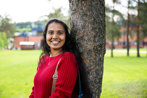 Student leaning on a tree and smiling