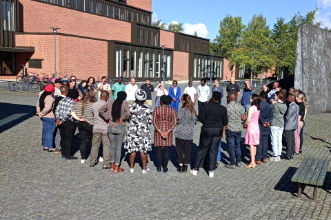 People gathered in a circle in the square in front of a building.