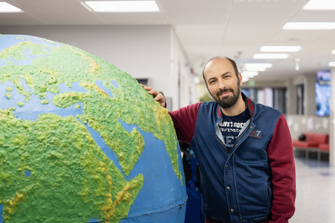 Student leaning on a giant globe