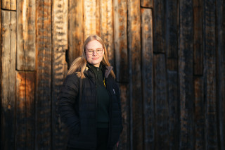 Metsätieteen opiskelija Helmi Karppinen hirsisinän edustalla