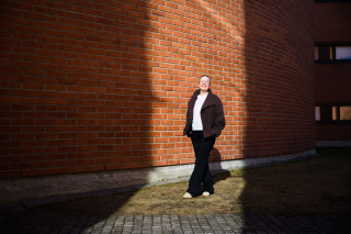 Opiskelija Tea Salo kampusrakennuksen seinustalla