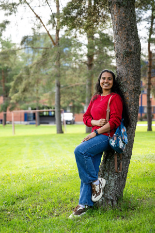 Student leaning on a tree and smiling