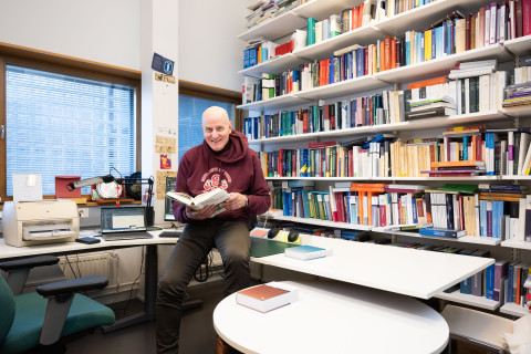 Matti Tolvanen työhuoneella kirjahyllyn vieressä.