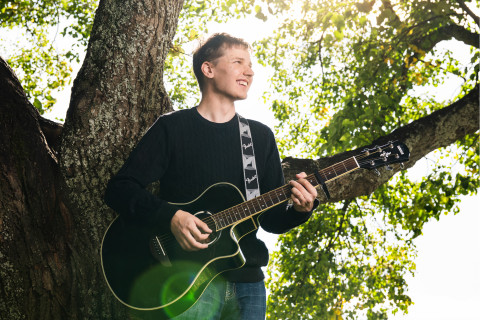 UEF-lähettiläs Konsta Kinnunen kitara kädessä