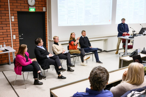 Panelisteja luentosalin etuosassa.